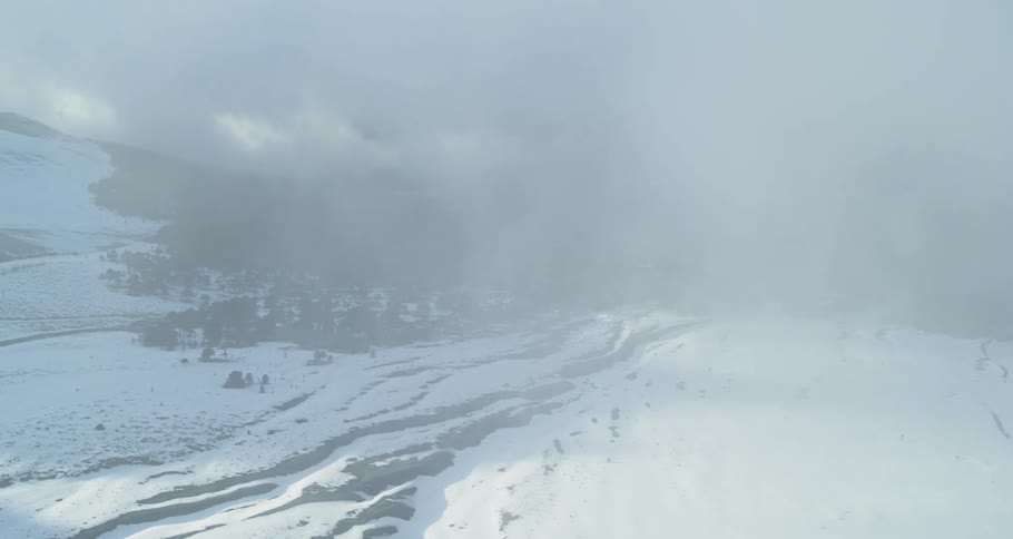 Aerial view through clouds revealing an ancient snowy landscape