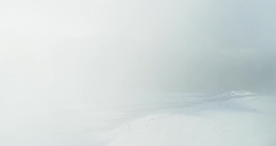 Aerial push through clouds revealing a stunning snowy landscape