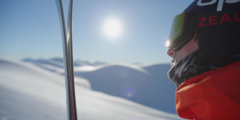 A skier stands and looks across the mountain