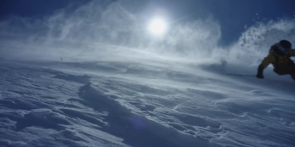 A skier dramatically sprays snow on a windy day