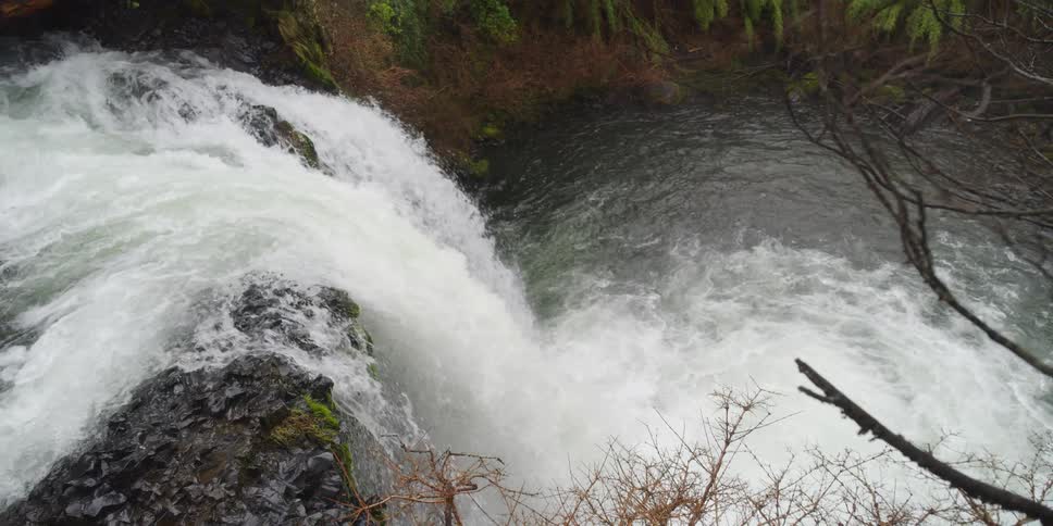 Waterfall flows over the rocks and splashes into the lake below