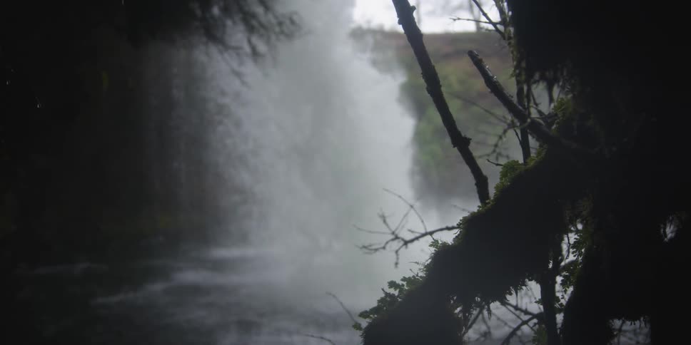 A waterfall spills into a river near a riverbank