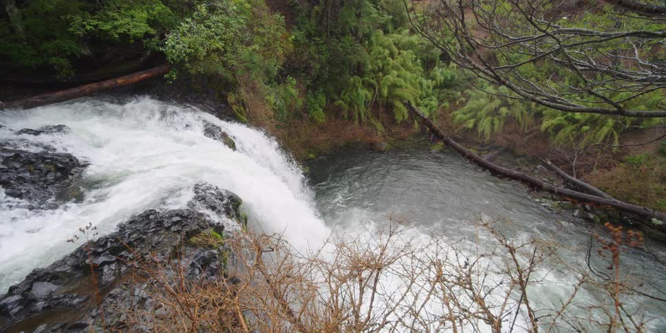A waterfall crashes to the water below