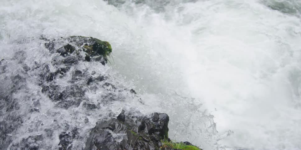 A waterfall tumbles over rocks and falls into a body of water