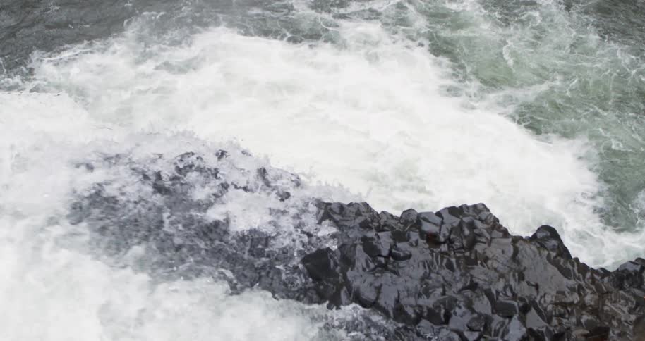 Aerial following water off the edge of a waterfall