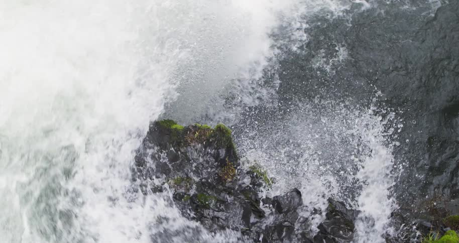 Aerial tracking closely above the lip of a waterfall