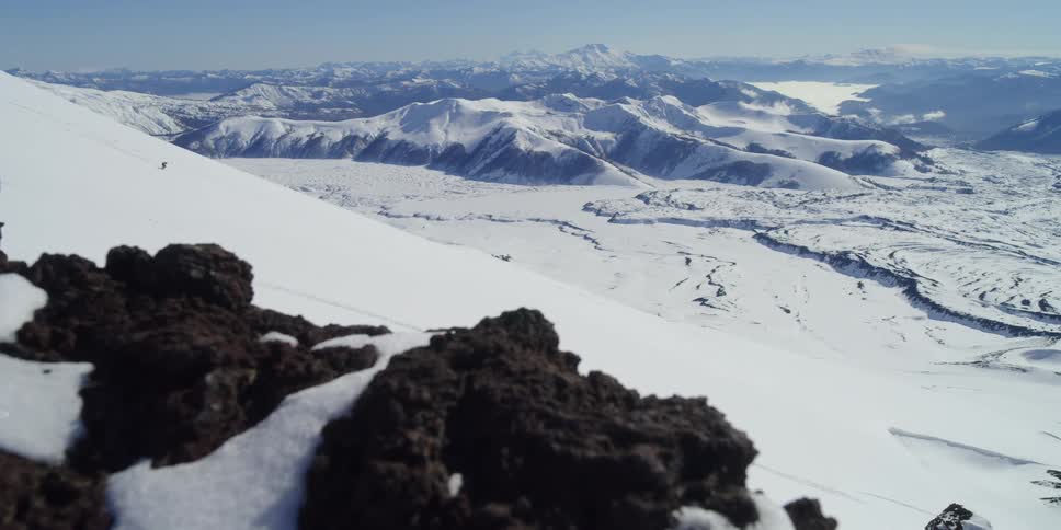 A person skis down a big slope in front of an incredible valley