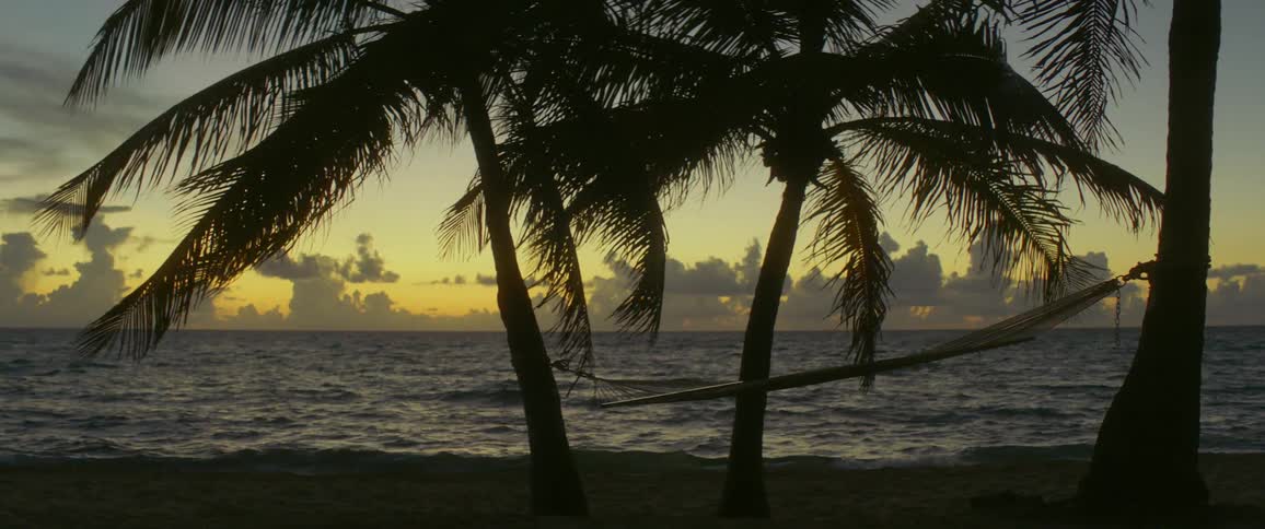 Hammock swaying and rough ocean waters on windy sunset in the tropics