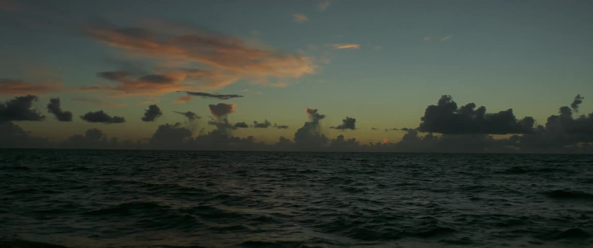 Ocean waves move across the water when the sun is below the horizon