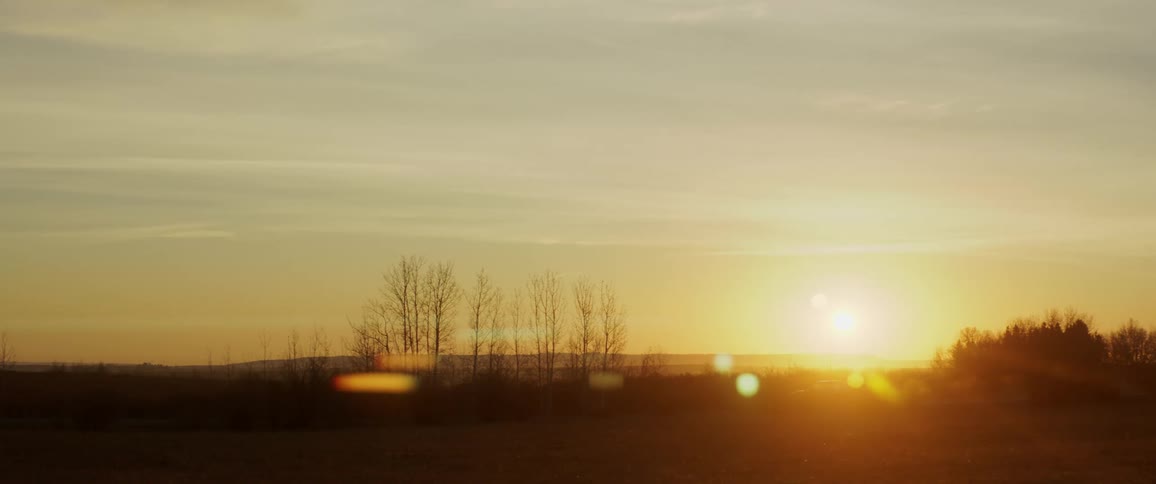 Pickup truck drives down country road at sunset