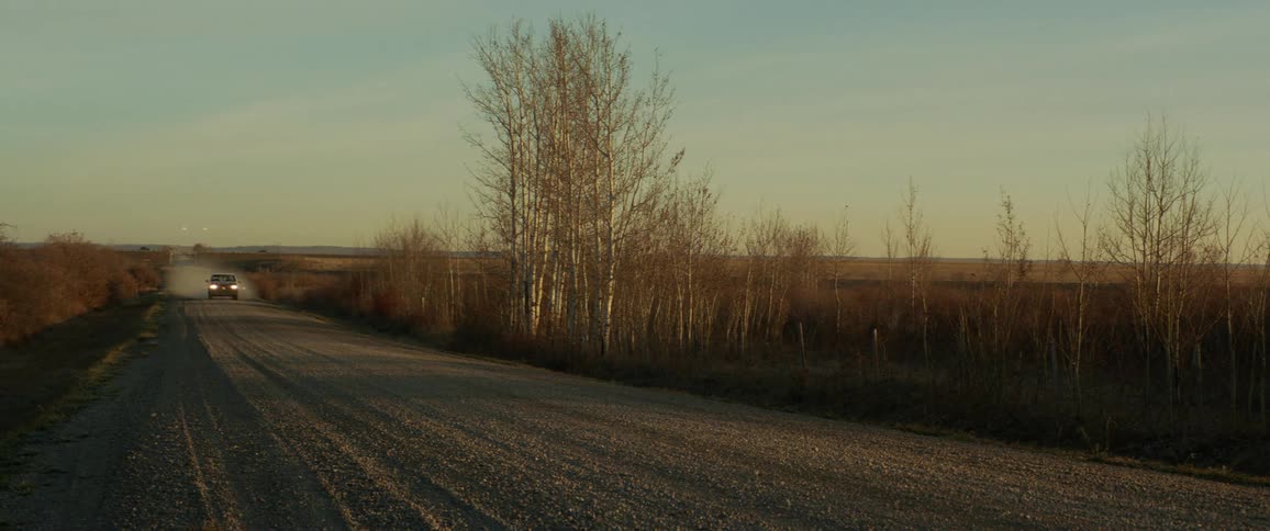 A truck drives down a rural gravel road