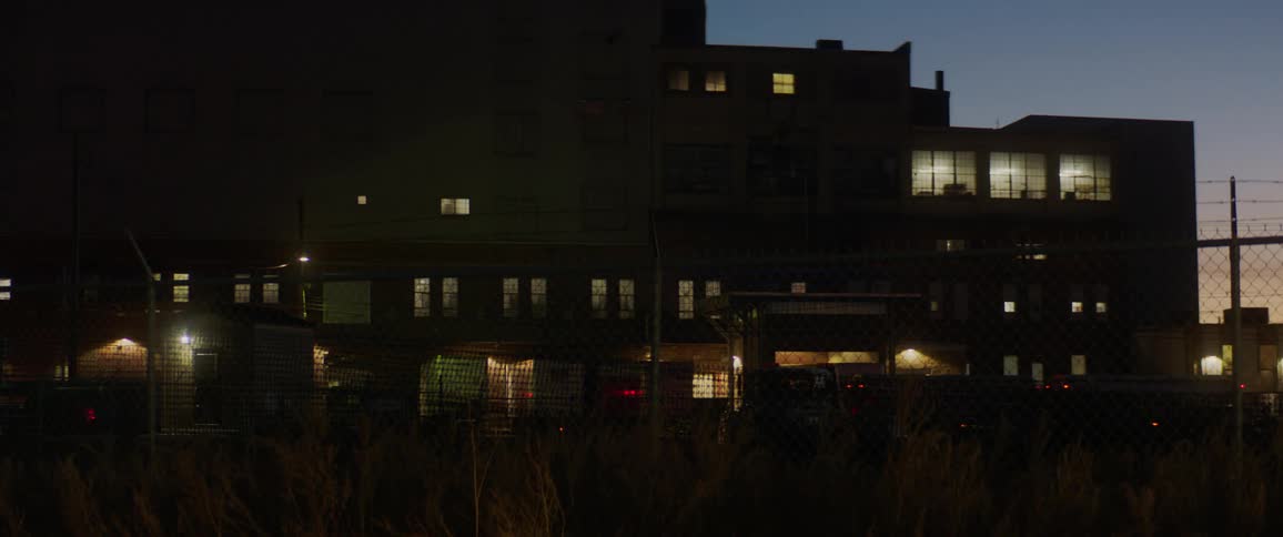 Red light flashes in front of a building at night as a vehicle travels past