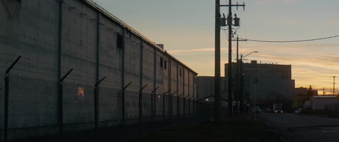 A street with vehicles buildings and a fence