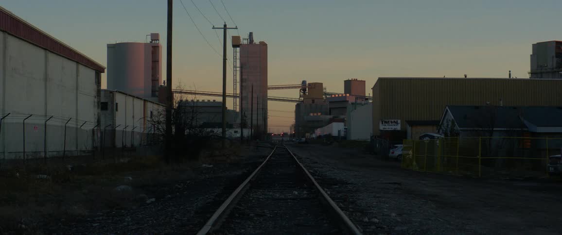 A train track runs between buildings and fences