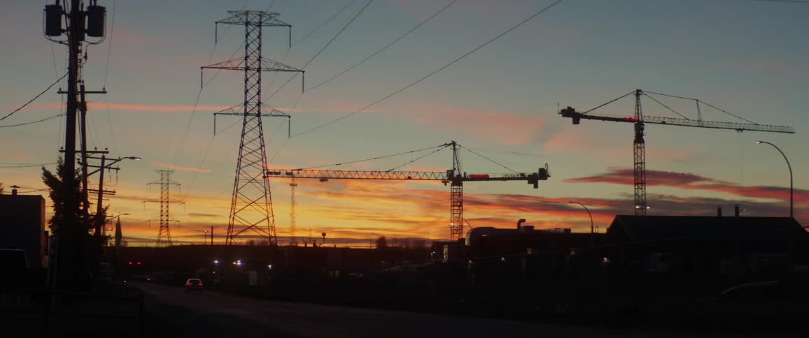 A vehicle driving on a road with cranes in the background