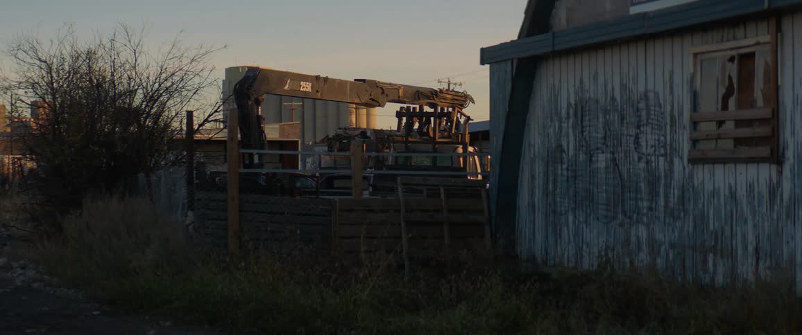 Farm equipment is parked near a dilapidated barn