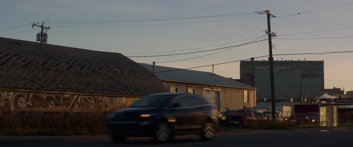 Traffic on city street in front of warehouse building covered in graffiti