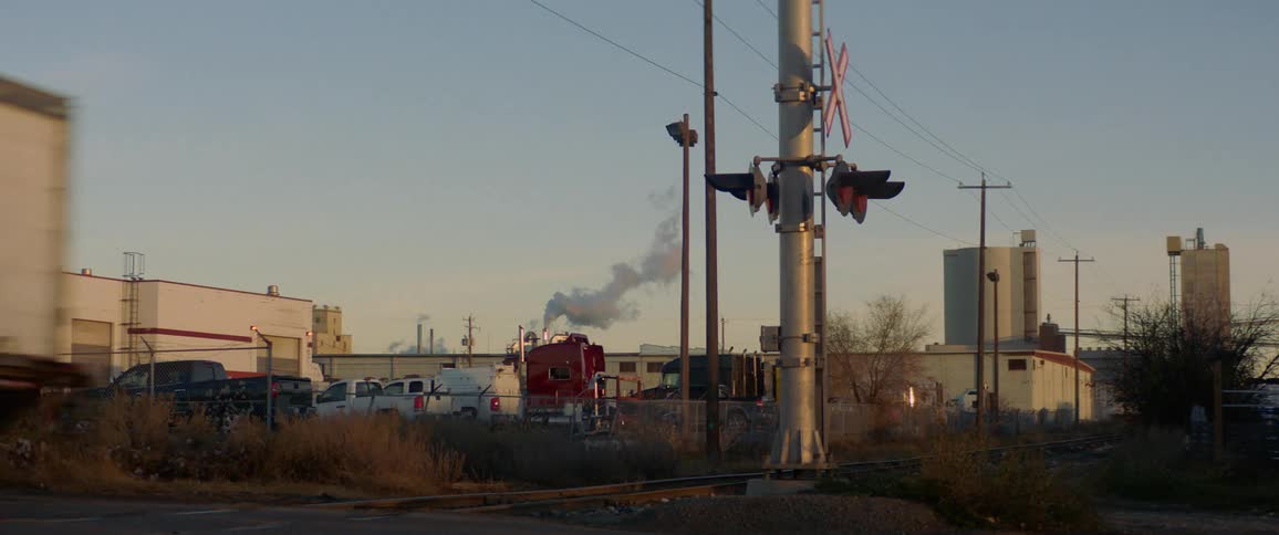 Box truck crosses railway crossing in industrial area
