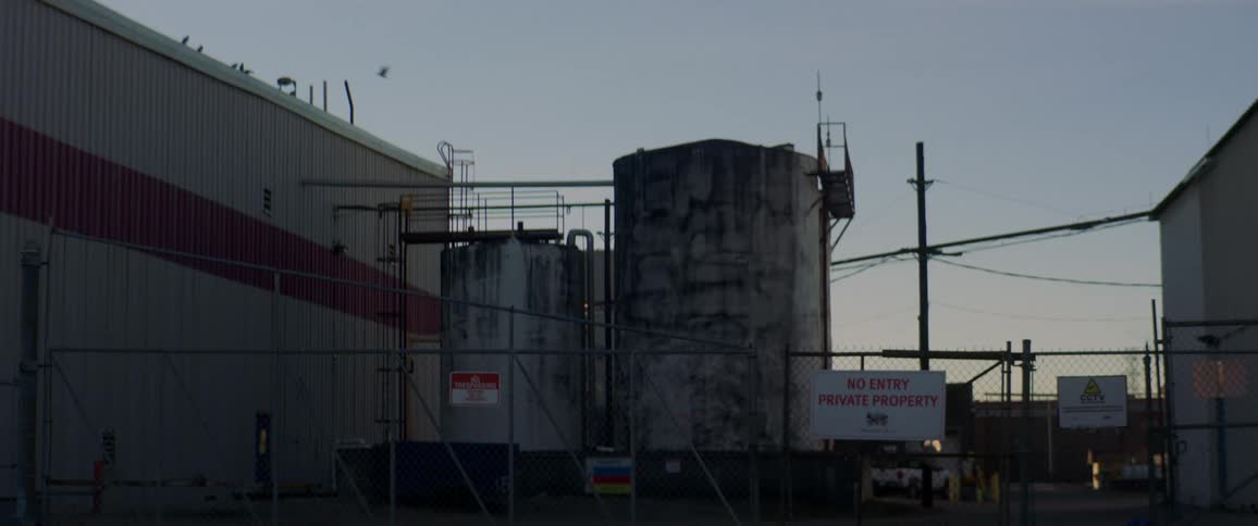 An industrial plant with large tanks behind a security fence