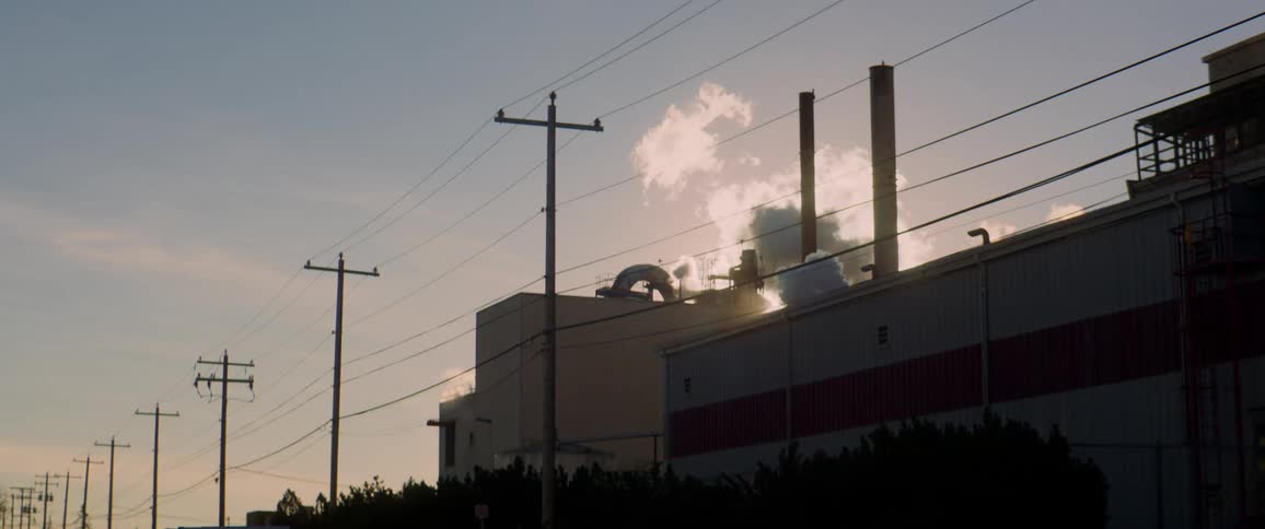 Smoke rises from smokestacks on the roof of a factory
