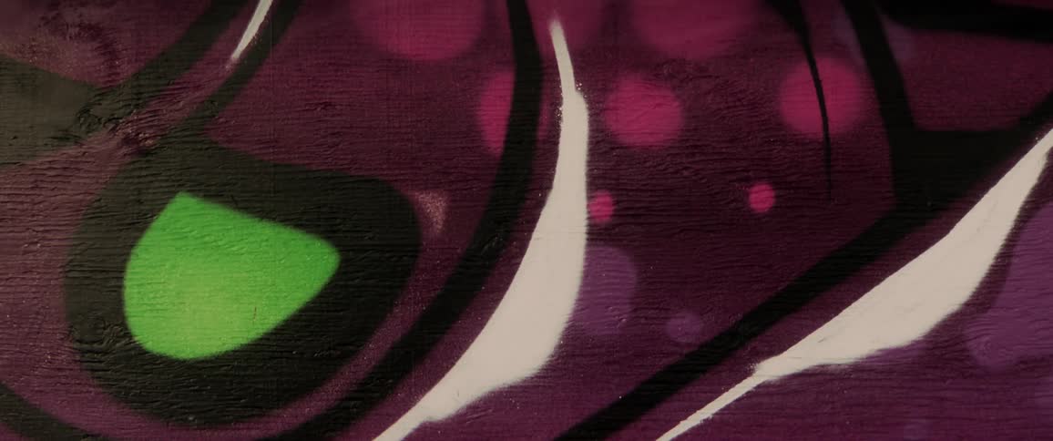 A mural consisting of purple and green shapes is painted on a concrete wall