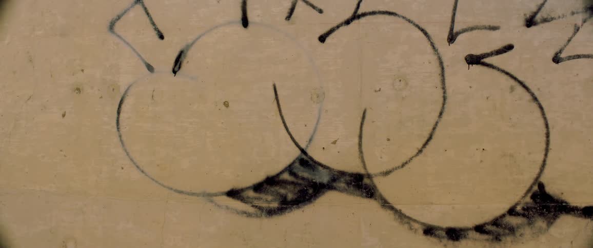 Black graffiti on the side of a building wall