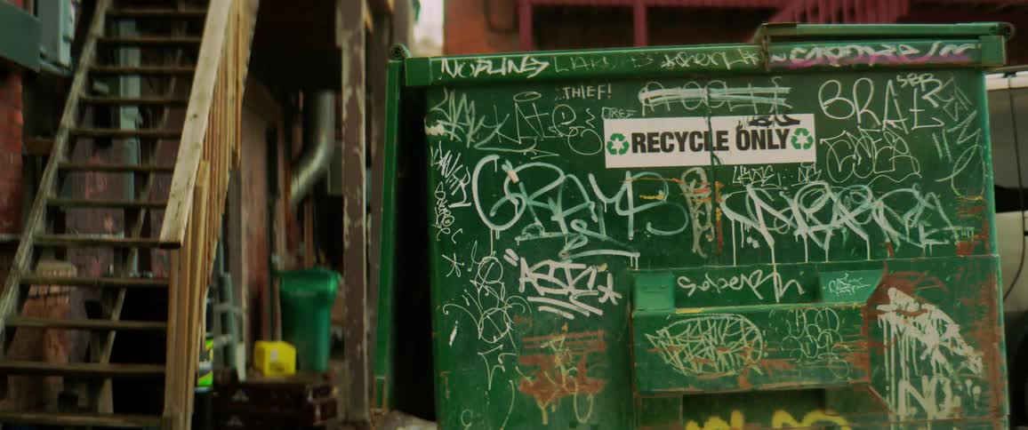 Blackboard with writing and graphics and a recycling sign sits next to an outdoor staircase