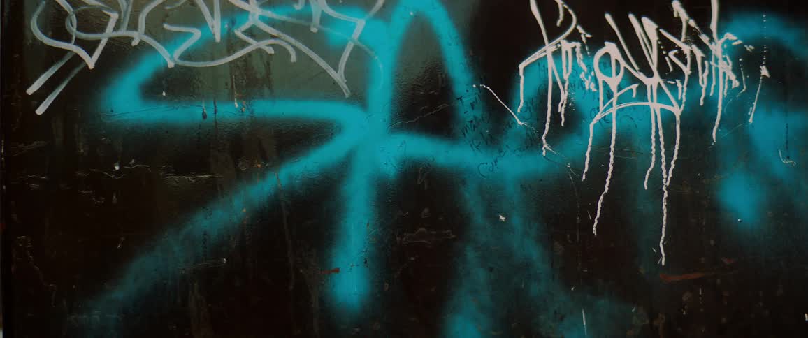 Graffiti painted on a glass surface with drips and streaks