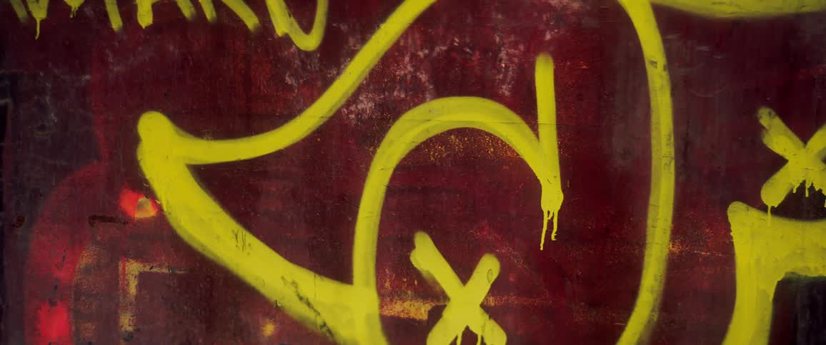Yellow graffiti spray painted on dark red wall