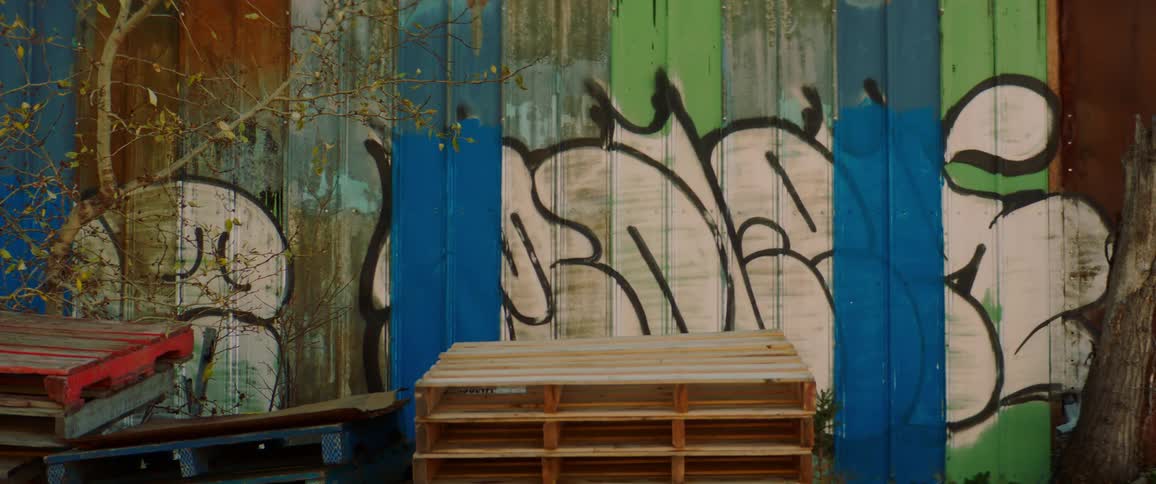 Wooden pallets stacked in front of a wall painted with graffiti