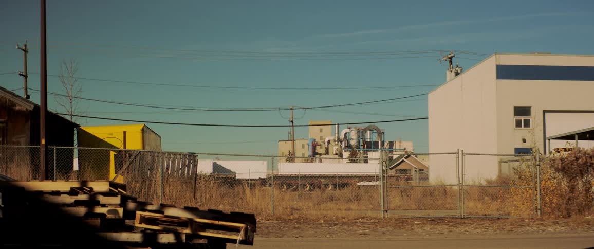An empty lot sits fenced in between two buildings