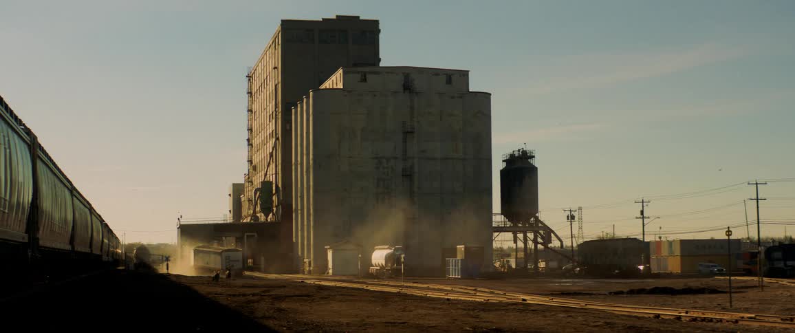 A shipping truck drives away from a factory