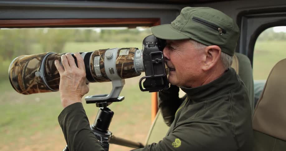 A man is using a long lens to take photos from a vehicle