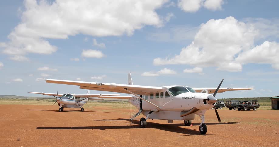 Small airplanes are parked on an open field in a rural area