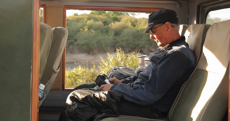 A photographer looks at his camera while sitting in a vehicle