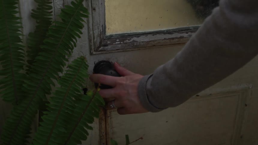 Person reaches out and opens old wooden door