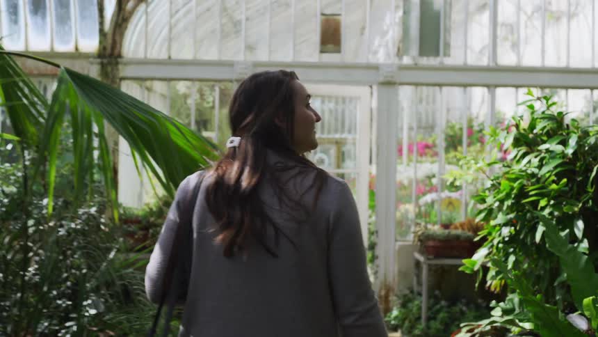 A woman walks through a greenhouse