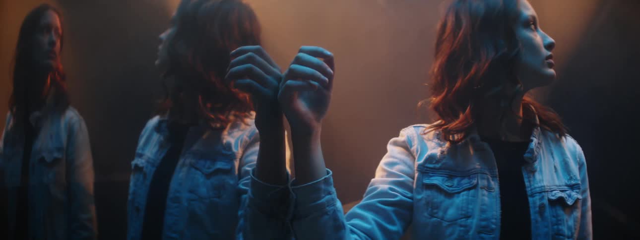 A woman stands against a mirrored wall and runs her down it
