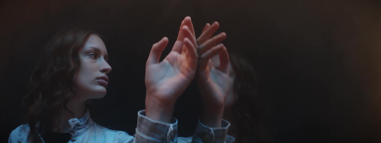 A teenager looks at her reflection and touches it