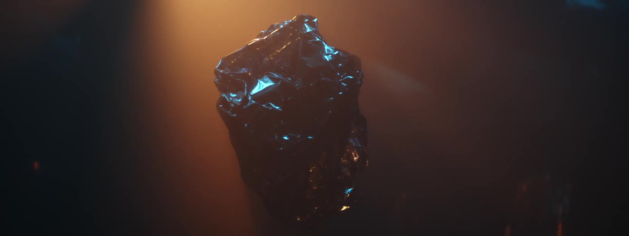 Chunk of crystalline stone glints and shines blue under light in shadowy room