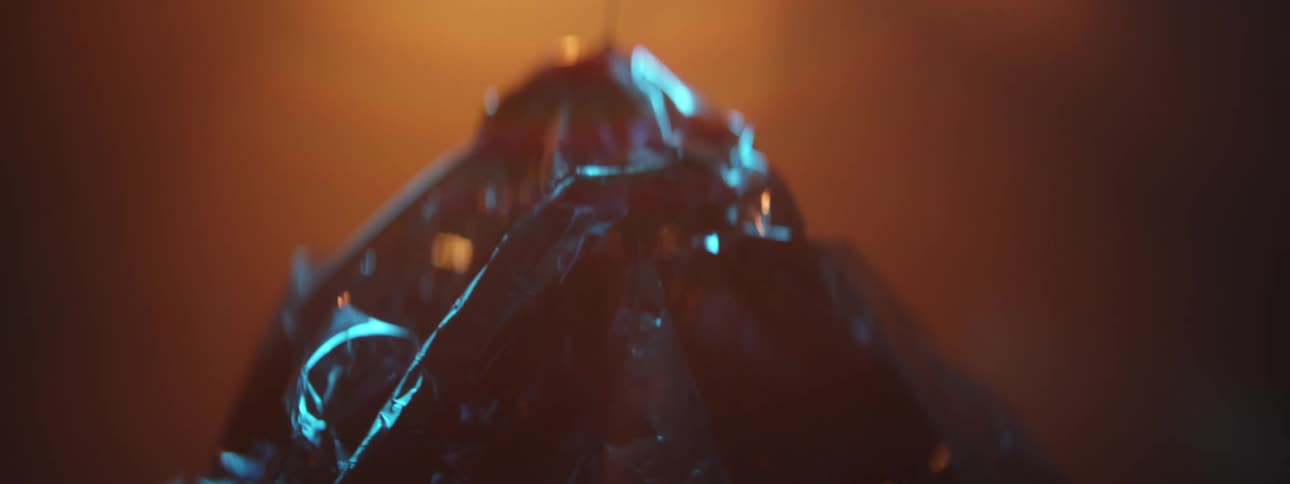 A crumpled mylar balloon shimmers and reflects glowing orange light