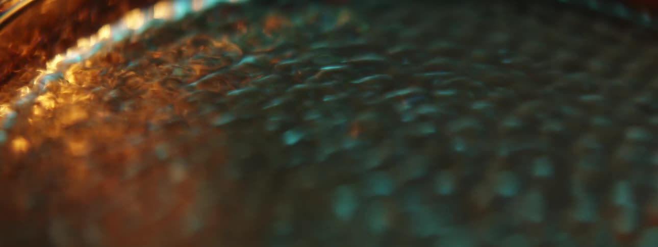 Clear liquid roils in shiny metal pan