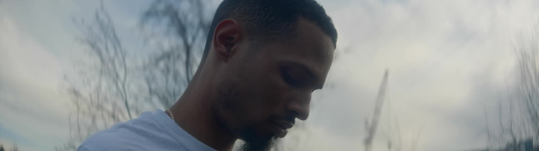 Side view of a black man looking down in the forest