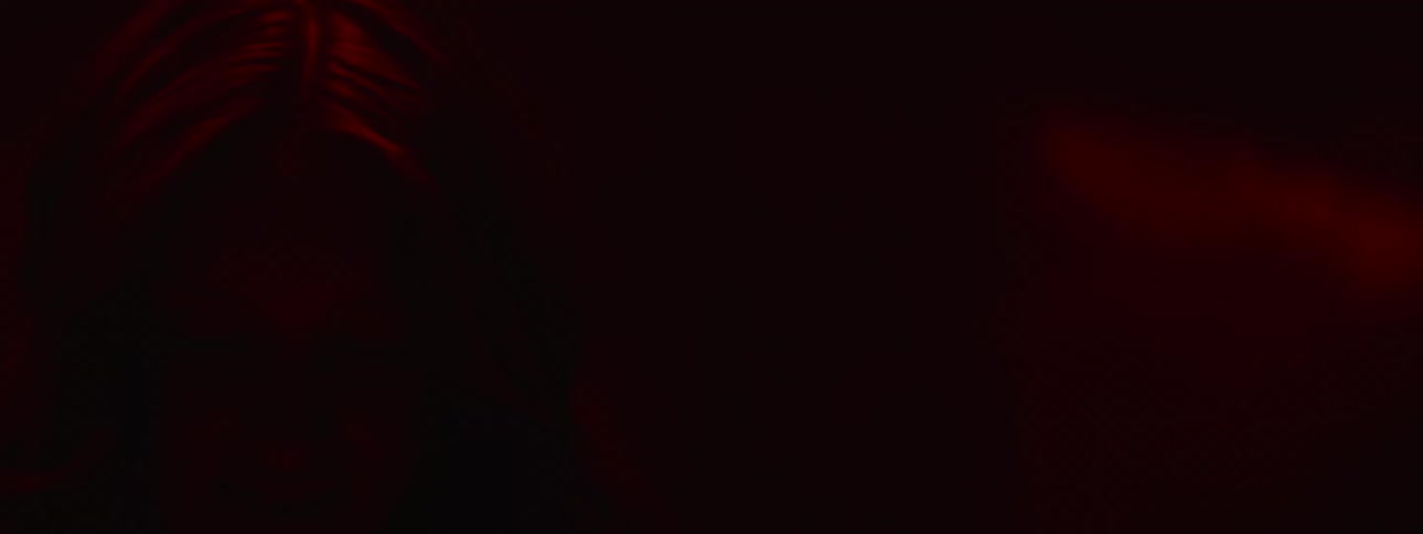 Red light shines on woman in dark shadows