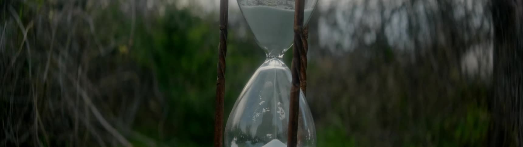 Sand flowing through hourglass sitting in grass outdoors