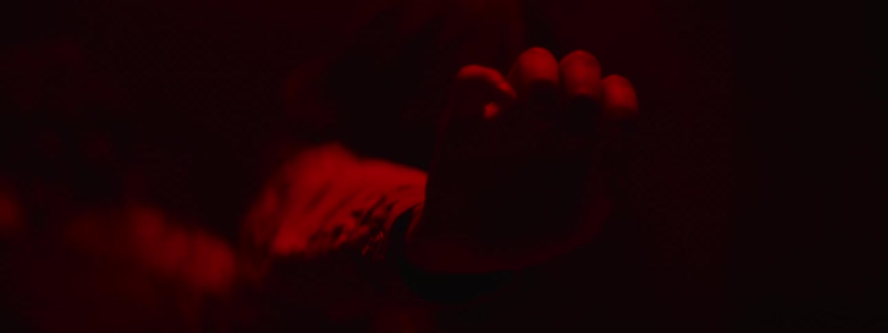 A young girl reaches her arm out in a dark room