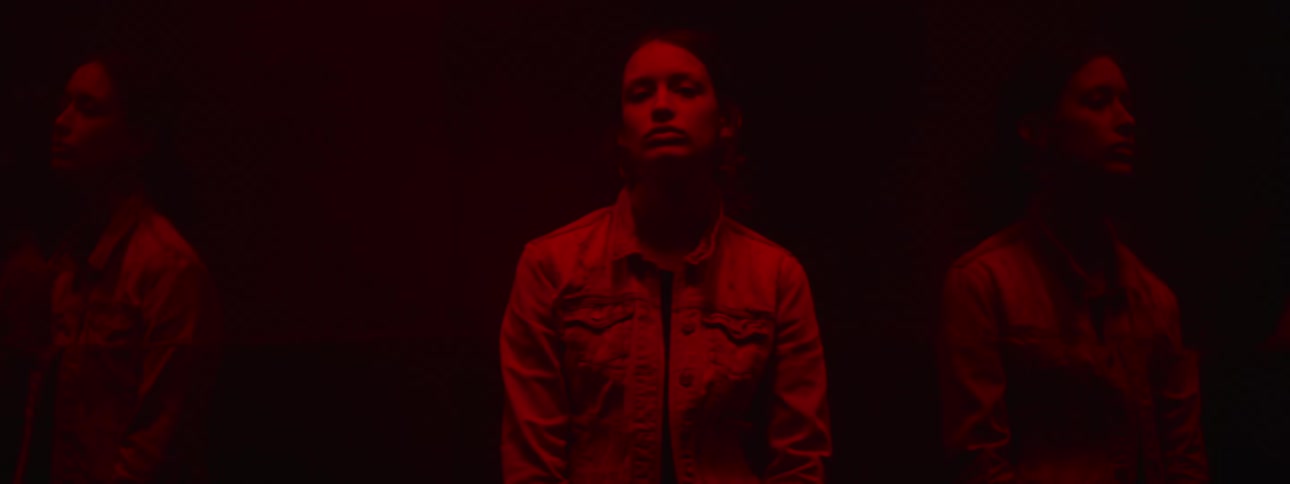 Young woman under red light reflected on each side in mirror surface