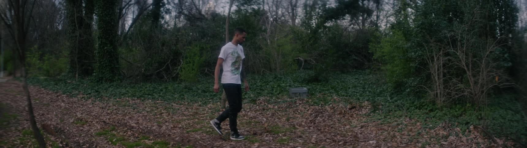A black man wanders around in a circle out in the woods