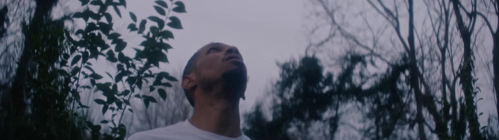 A man stands in a forest and looks around