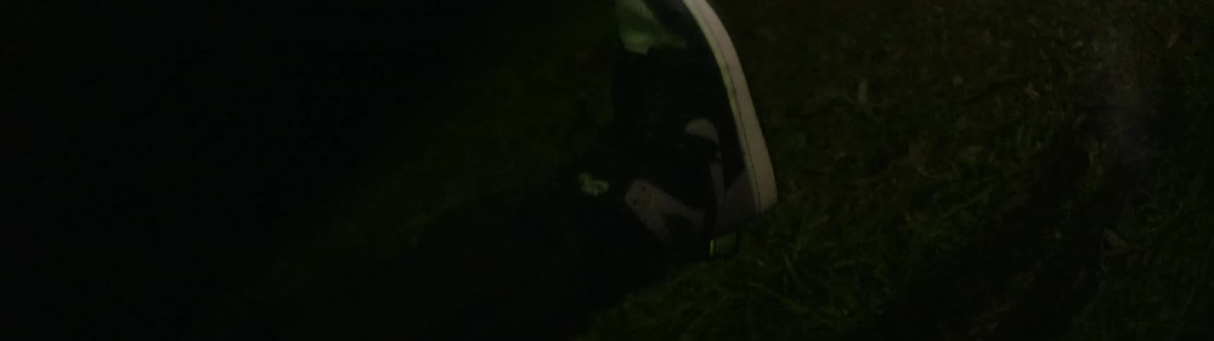 A man raises his feet and legs off the grass at night